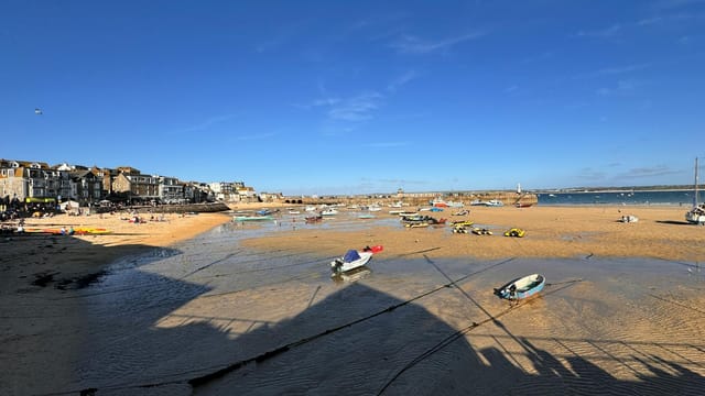 Explore the picturesque St Ives beach, boats, and vibrant seaside community in England.