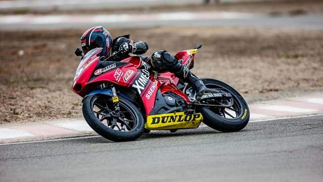 Motorcycle racer leaning into a turn on a professional racing circuit.