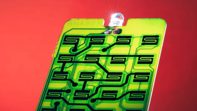 Close-up of a green circuit with intricate patterns on a vibrant red background, ideal for technology themes.