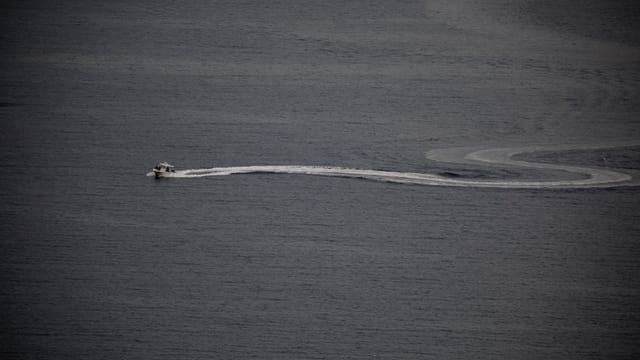 Aerial view of a motorboat creating a curved wake in open water, perfect for boating enthusiasts.