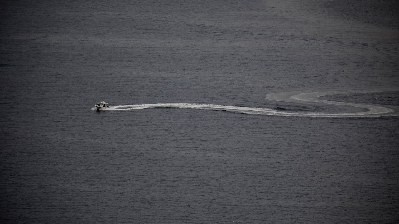Aerial view of a motorboat creating a curved wake in open water, perfect for boating enthusiasts.