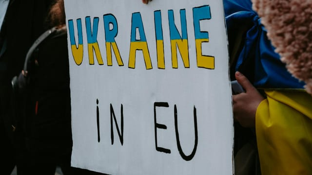 A protest sign advocating Ukraine's membership in the EU, held by demonstrators outdoors.