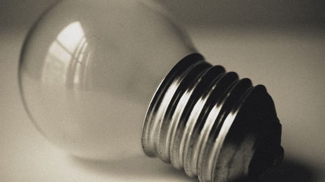 A vintage-style close-up of a lightbulb reflecting window light.