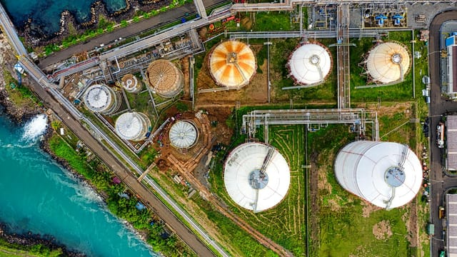 Aerial view of an industrial complex near a river in Banten, Indonesia, showcasing storage tanks.
