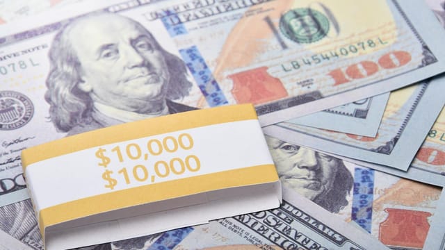 Close-up of $100 US dollar banknotes wrapped with a $10,000 band, symbolizing wealth and financial success.