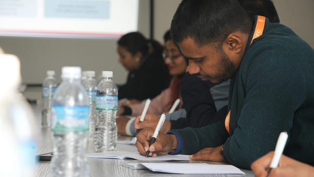 Focused students taking notes during a classroom seminar indoors.