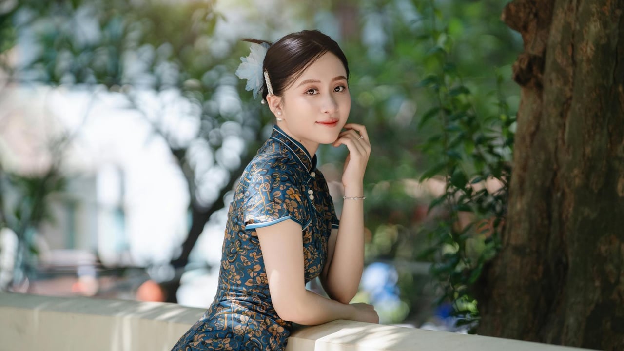 A woman in a traditional dress posing gracefully outdoors under natural sunlight.