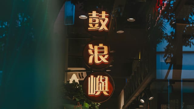 A vibrant neon sign highlights a modern storefront in the evening.