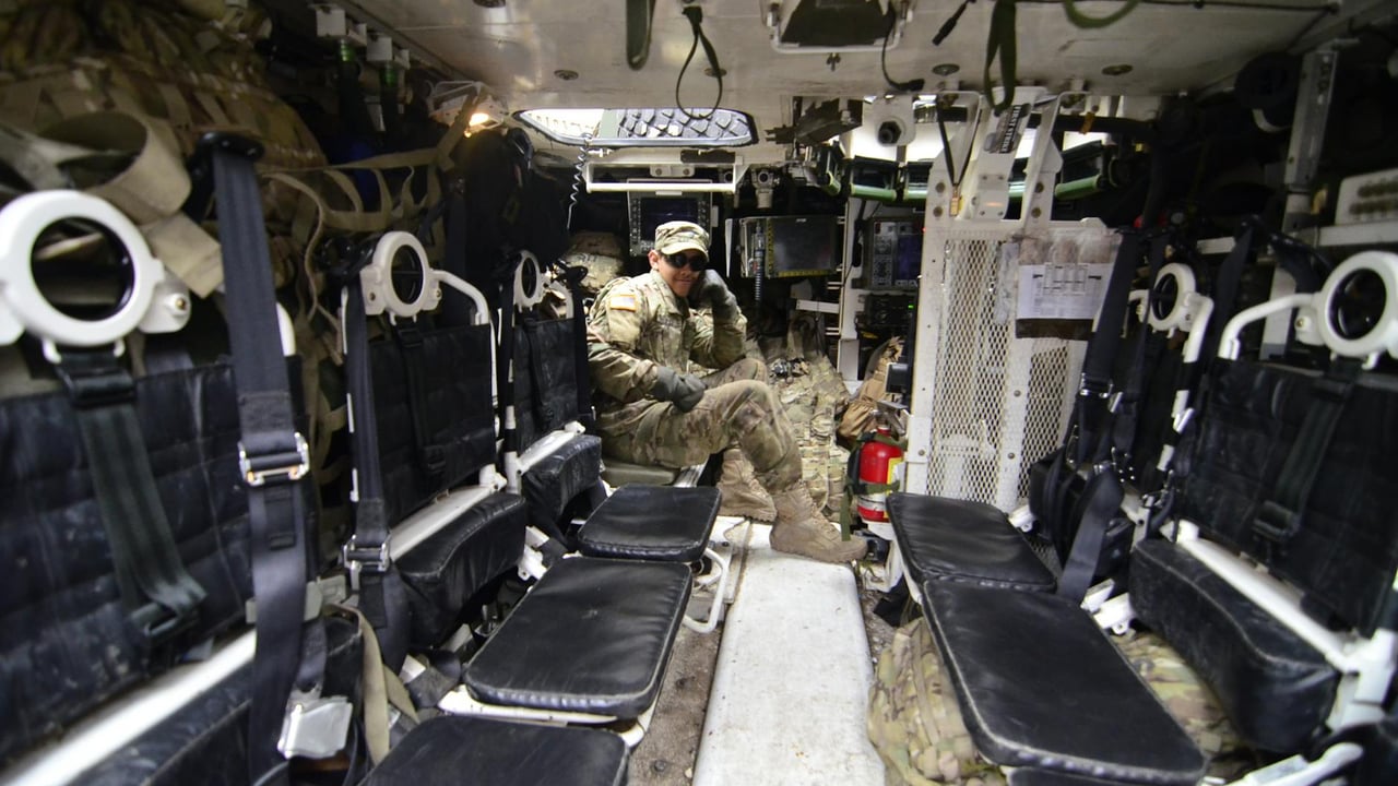 Soldier inside an armored vehicle, showcasing military equipment and seating.