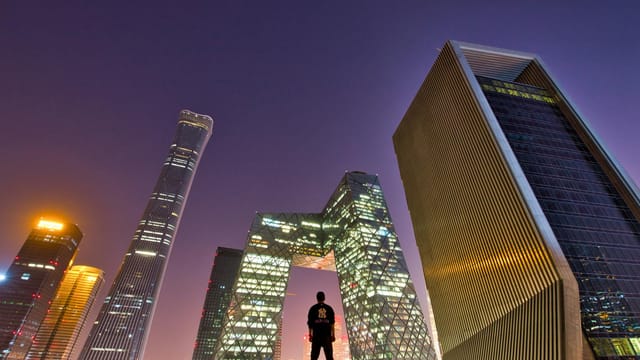Silhouette of a man overlooking Beijing's skyline at twilight. Modern architecture in focus.