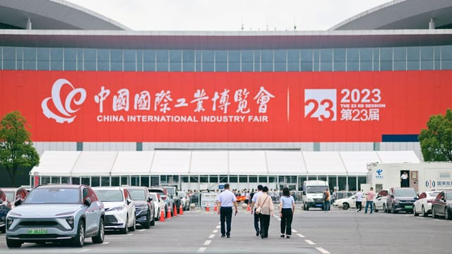 Entrance to China International Industry Fair 2023 in Shanghai, featuring people and cars.