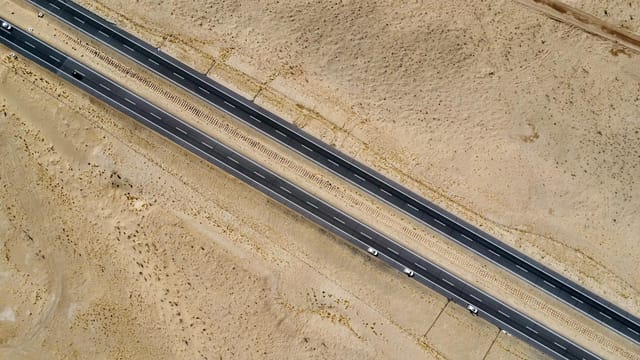 Drone aerial view of a highway cutting through the barren desert landscape in Xinjiang, China.