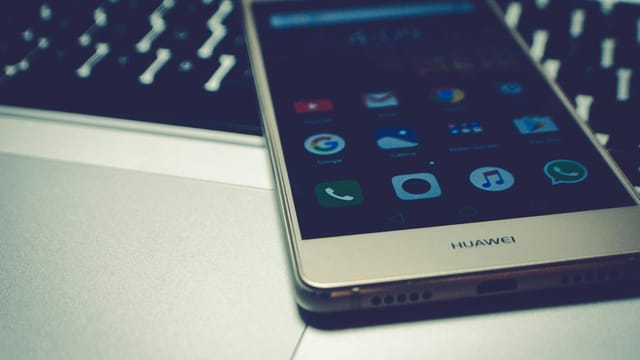 Close-up of a smartphone placed on a laptop keyboard, highlighting digital interaction.