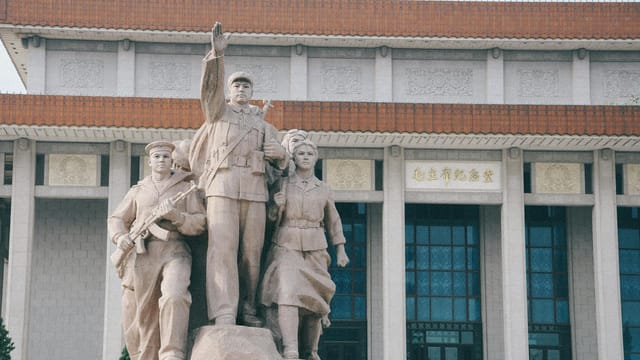 A commanding statue of soldiers in front of a historic building with traditional architecture.