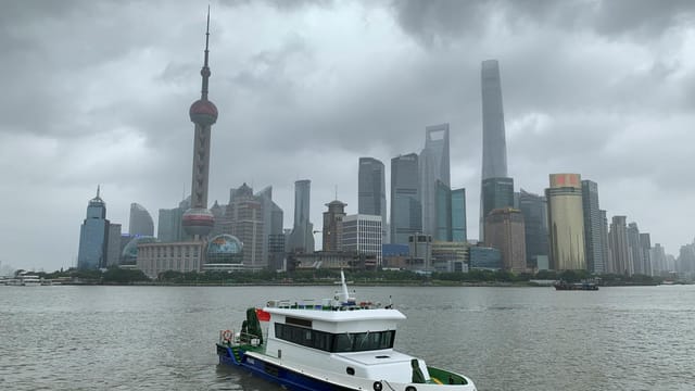 Dramatic view of Shanghai skyline with Oriental Pearl Tower and boat on Huangpu River.