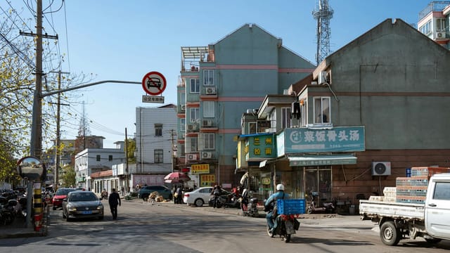 Busy street scene in Shanghai featuring local shops and urban architecture under clear blue skies.