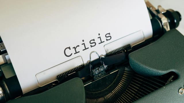 Close-up of a vintage typewriter with the word 'Crisis' typed on paper.