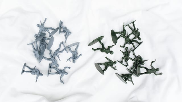 Colorful army toy figures arranged on a white cloth in aerial view.