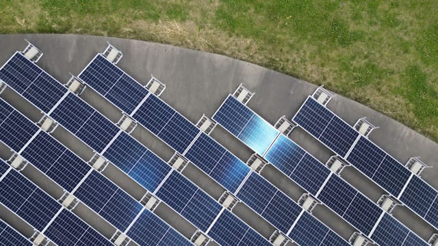Top-down view of solar panels arranged on a green field, highlighting renewable energy.