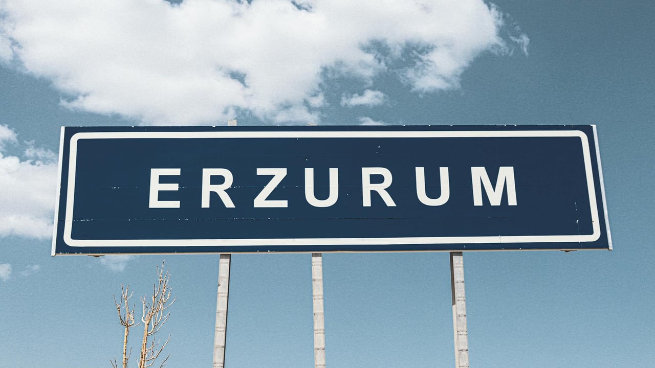 Street sign for Erzurum against a backdrop of a bright blue sky and fluffy clouds.