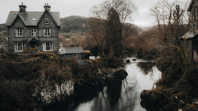 Picturesque old stone house by a tranquil river in Betws-y-Coed, Wales.