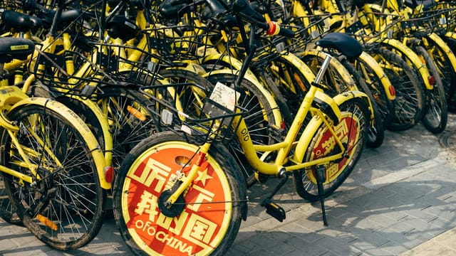 A fleet of yellow shared bicycles parked on a city sidewalk indicating urban mobility solutions.