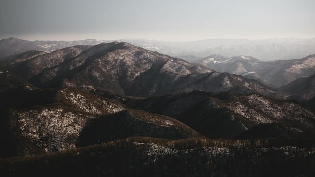 Breathtaking aerial view of Pyeongchang's snow-capped mountains under a clear sky.