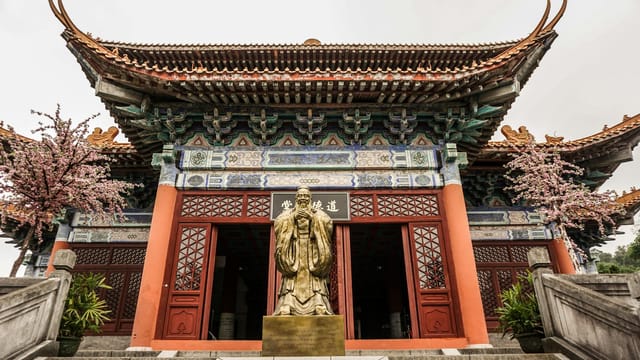 A detailed view of a golden statue in front of an ornate temple entrance in Guangzhou, China, showcasing traditional architecture.