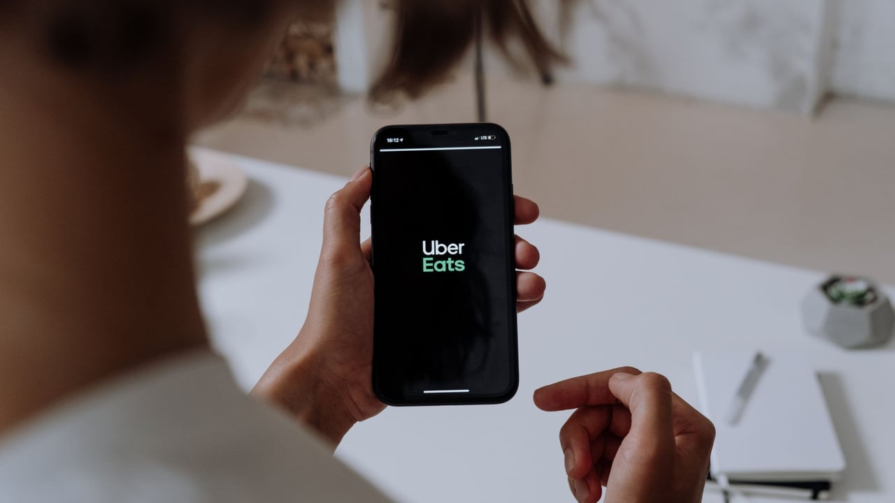 Person holding a smartphone using Uber Eats. Indoor setting with a clear view of the app interface.