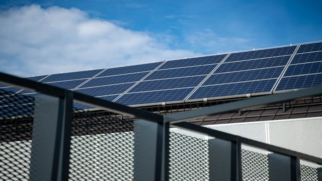 Illustrative image: Close-up view of modern solar panels on a rooftop against a clear blue sky, representing clean energy.