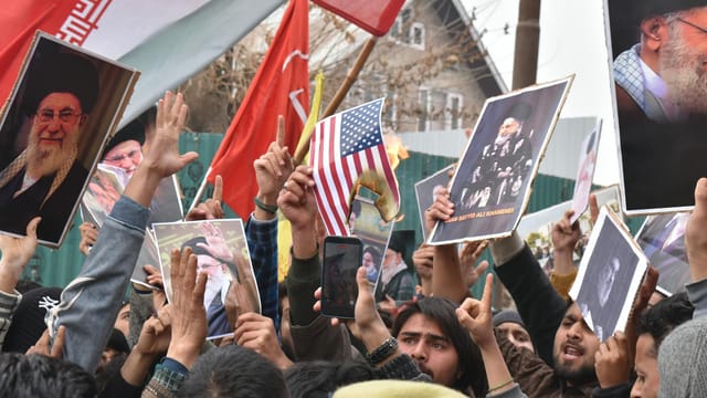 Crowd of demonstrators holding flags and banners during a protest outdoors.