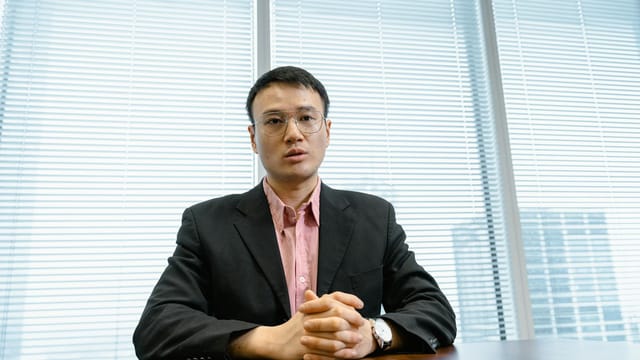 Businessman in a suit poised at his desk, exuding leadership in a modern office setting.