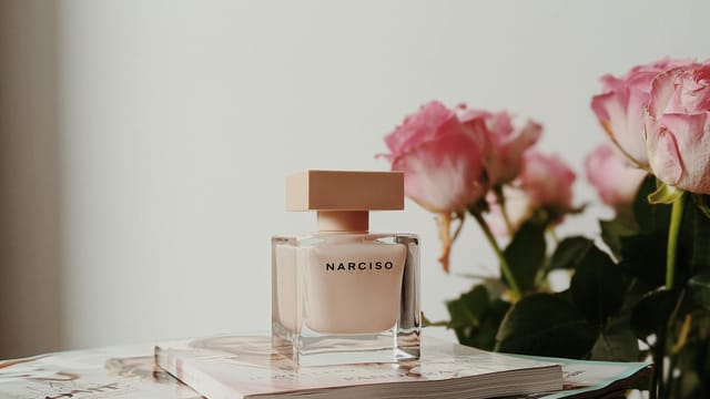 Sophisticated Narciso perfume bottle with pink roses and magazines. Perfect for elegance and fragrance themes.