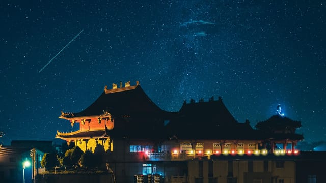 A beautiful Taiwanese temple illuminated at night beneath a clear starry sky, showcasing cultural architecture.