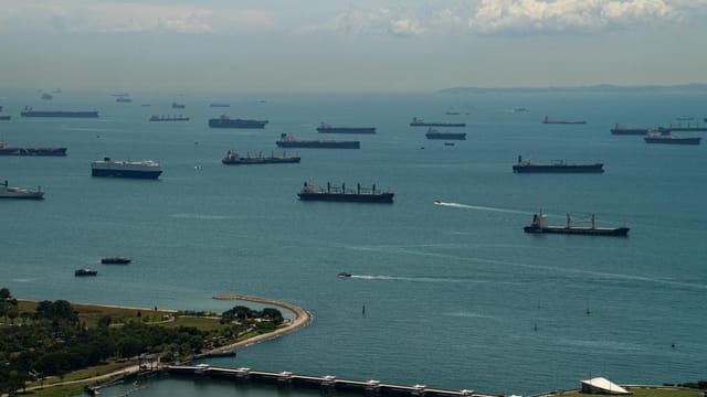 Aerial view of ships anchored in the Singapore Strait under a clear sky, showcasing maritime activity.