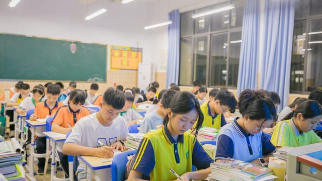 A group of students writing in a classroom during a lesson.