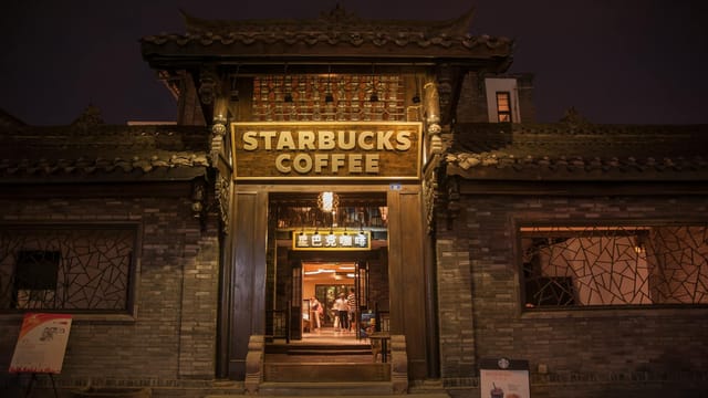 Exterior view of a Starbucks located in a traditional Chinese style building during nighttime.