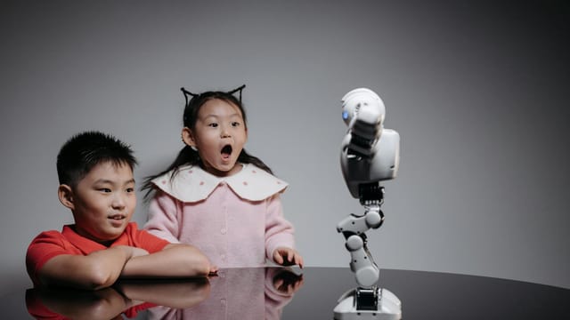 Two children fascinated by a toy robot, showcasing excitement and curiosity indoors.