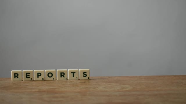 Scrabble tiles spelling 'reports' on a wooden desk, ideal for office or business themes.
