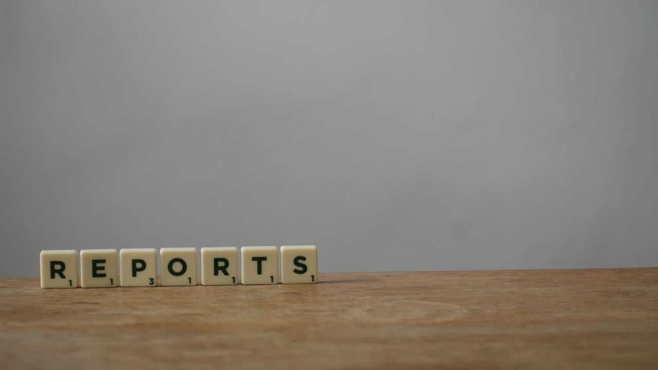 Scrabble tiles spelling 'reports' on a wooden desk, ideal for office or business themes.