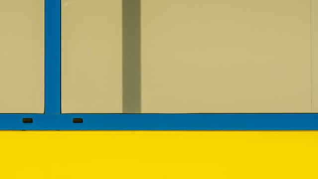 A minimalist abstract photo of a window facade showcasing vibrant blue and yellow colors.