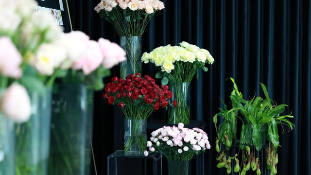 A stunning display of colorful flowers in glass vases against a dark curtain backdrop, perfect for event decor.