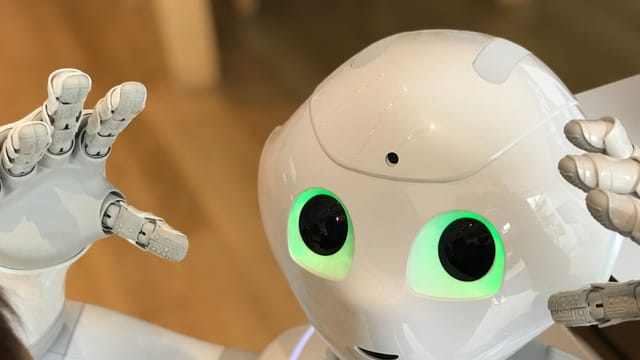 A futuristic humanoid robot with glowing green eyes in a modern setting.