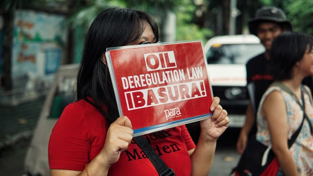 A woman holds a protest sign advocating against the oil deregulation law.