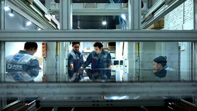 Engineers collaborate over advanced machinery in a high-tech indoor workspace.