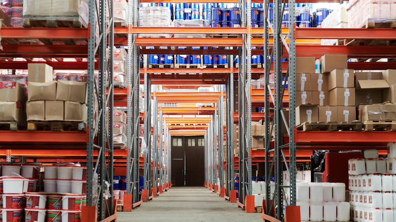 Wide angle view of a warehouse with stocked shelves and boxes.