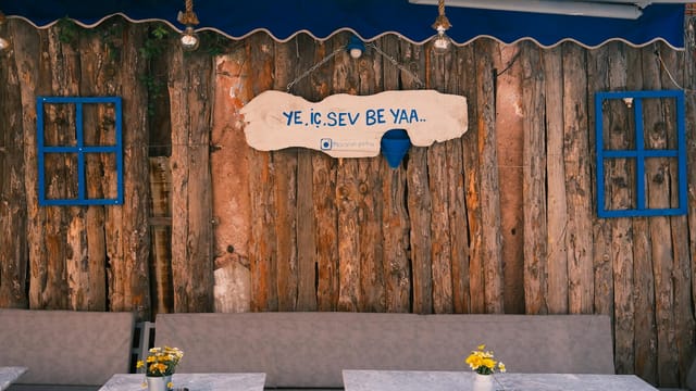 Charming rustic café setting with a wooden background, sign, and minimalist seating.