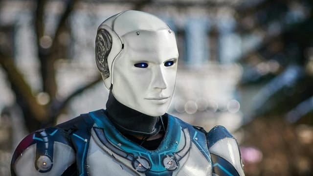 Close-up of a futuristic humanoid robot with metallic armor and blue LED eyes.