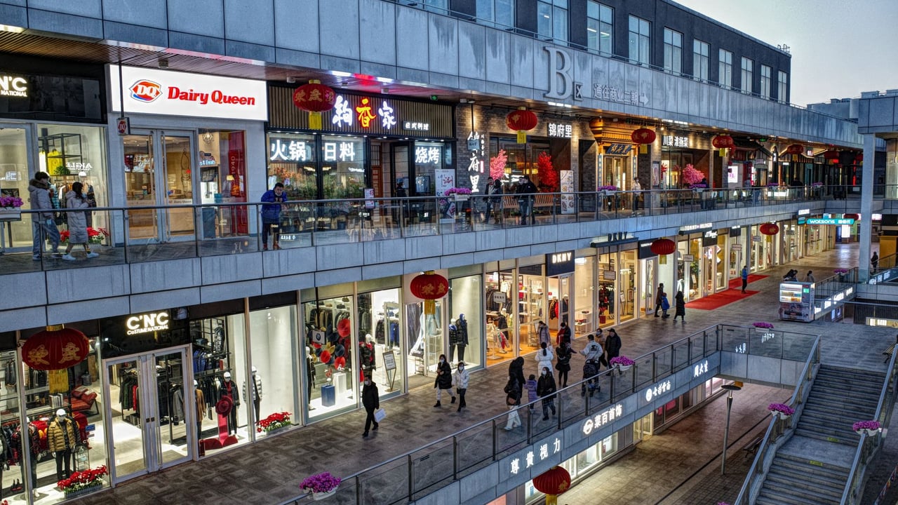 Bustling evening at a modern shopping mall with various shops and pedestrians.