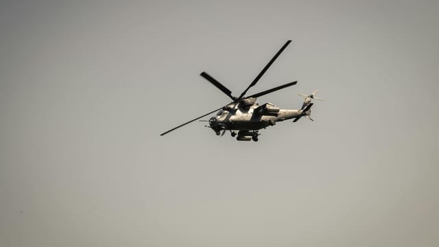A military attack helicopter flying against a gray sky, showcasing defense technology.